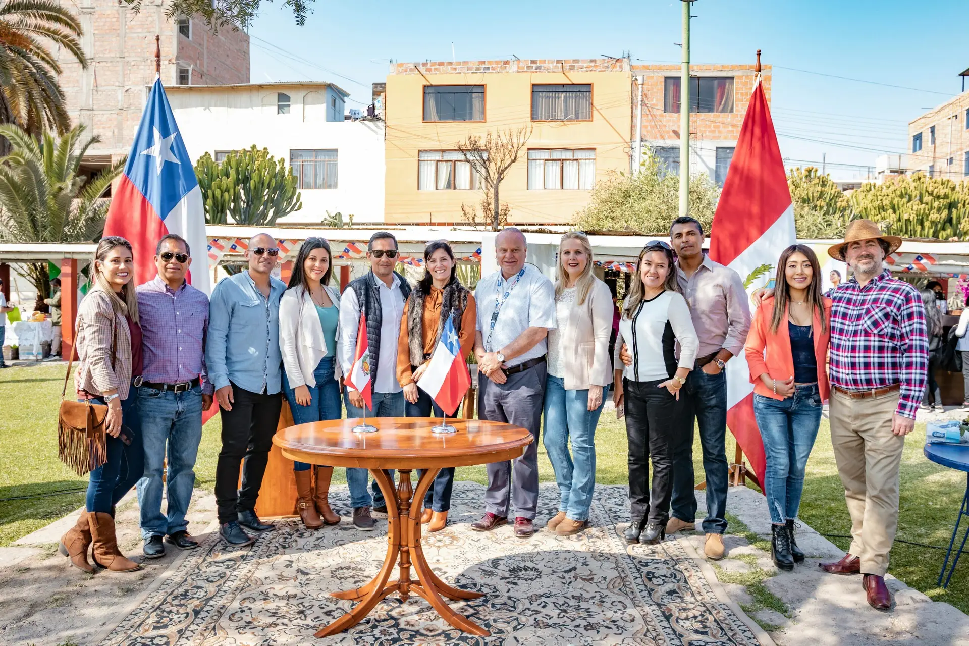 People standing together outdoors with Chilean and Peruvian flags in Tacna, Peru.
