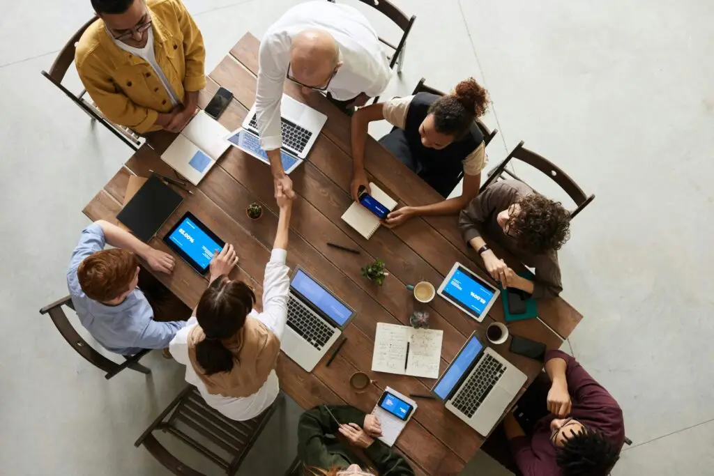 Top view of a diverse team collaborating in an office setting with laptops and tablets, promoting cooperation. Suad Design Studio